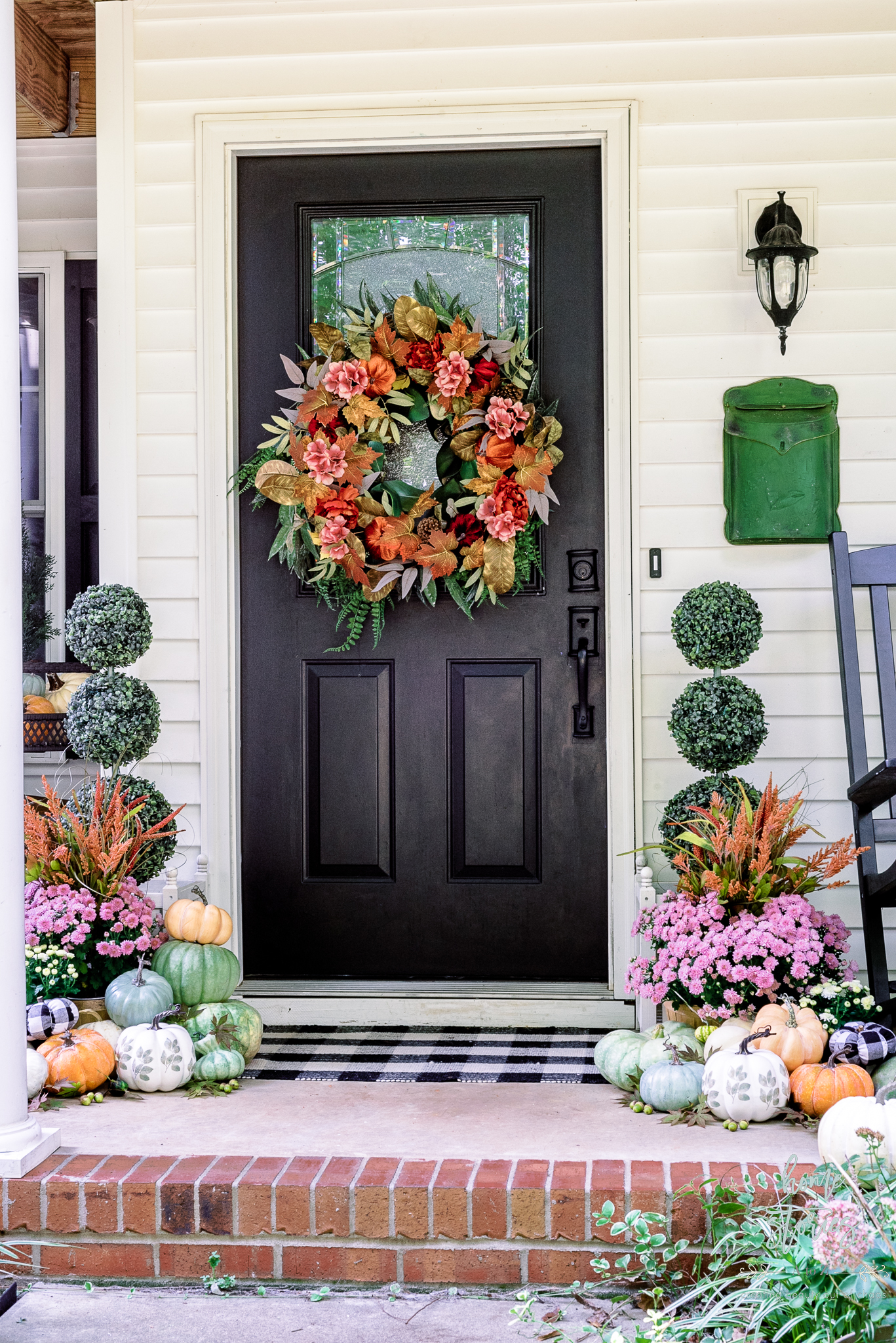 Fall porch decor with faux and live plants and pumpkins. Beautiful layered fall wreath with topiaries, mums, and multi-colored pumpkins